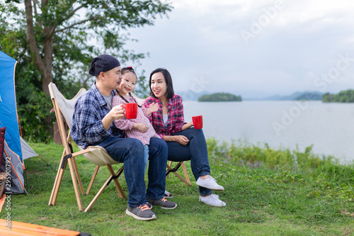 asian family travel and camping in forest, they sitting and drinking hot coffee at lakeside , family activity, adventure and travel