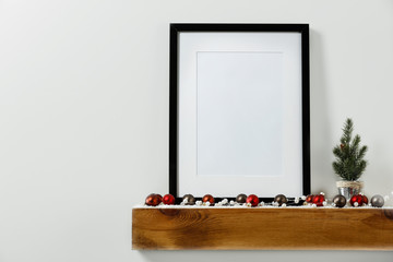 Christmas decorations in bright shiny colors with Christmas lights, picture frames and blurred white wall background.