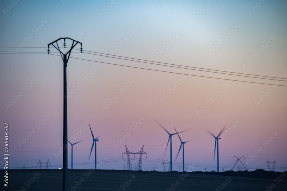 Un viento lejano con turbinas eólicas en un entorno de puesta de sol poético, que sirve como una imagen perfecta para la energía verde sostenible renovable.	
