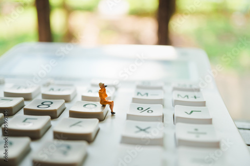 Miniature people, woman sitting on calculator using as business concept