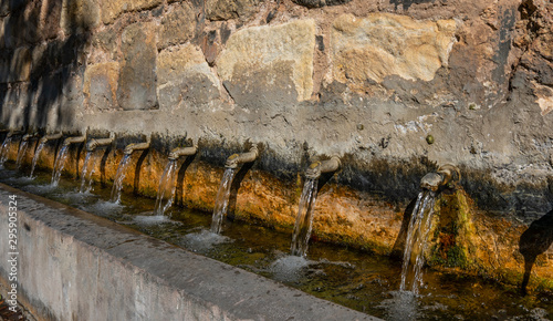 Cuadro en lienzo old water fountain on a stone wall with ten sources ready to drink - Image