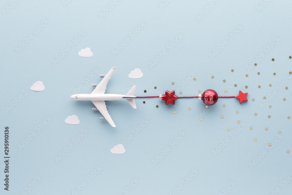 Fototapeta Christmas composition. Airplane flying in sky star gift bauble clouds top view background with copy space for your text. Flat lay.