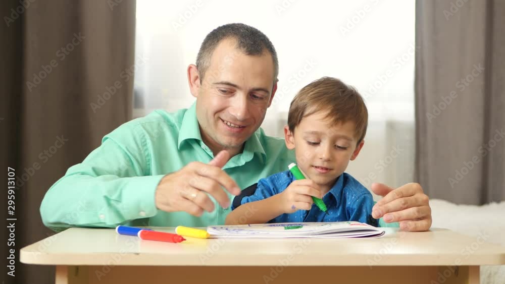 Dad and son spend time painting with colored felt pen. The concept of a happy family. Dad and son spend time painting with colored felt pen. The concept of a happy family.