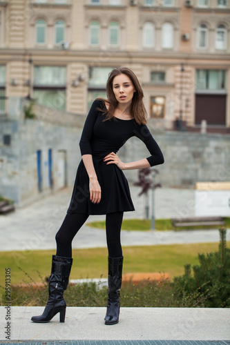 Portrait of young beautiful woman in black dress posing in autumn park on a background of Red Square in Moscow