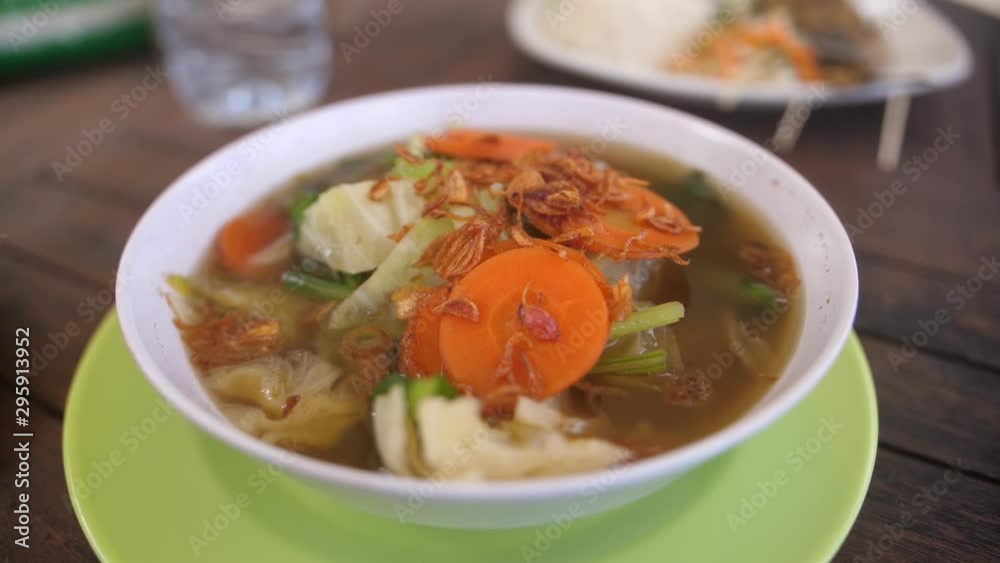 A simple vegetable soup served in a plastic bowl on a plastic plate in a local Balinese warung restaurant. A simple vegetable soup served in a plastic bowl on a plastic plate in a local Balinese warung restaurant.
