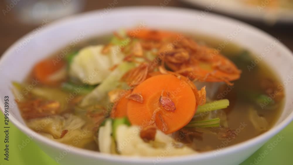 Close up of a simple vegetable soup served in a plastic bowl on a plastic plate in a local Balinese warung restaurant. Close up of a simple vegetable soup served in a plastic bowl on a plastic plate in a local Balinese warung restaurant.