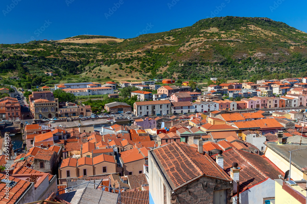 Panoramic view of Olbia, Sardinia, Italy. Historic old buildings with red rooftiles. Hill and blue sky in background.
