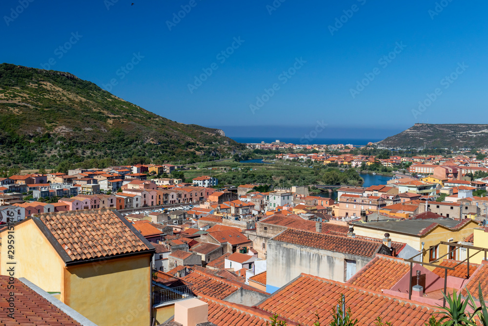Panoramic view of Olbia, Sardinia, Italy. Historic old buildings with red rooftiles. Hill and blue sky in background.