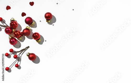 Red Christmas decoration, sparkles and confetti on white background. Xmas and New Year greeting card, winter holiday. Flat lay, top view, harsh shadow