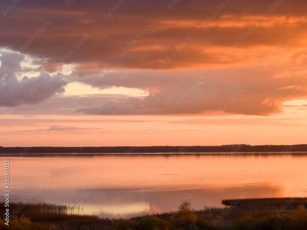 Beautiful serene colored sunset over Burtnieku lake  and lake reflections of the sky above, Latvia 