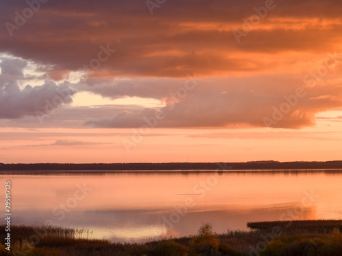 Beautiful serene colored sunset over Burtnieku lake and lake reflections of the sky above, Latvia 