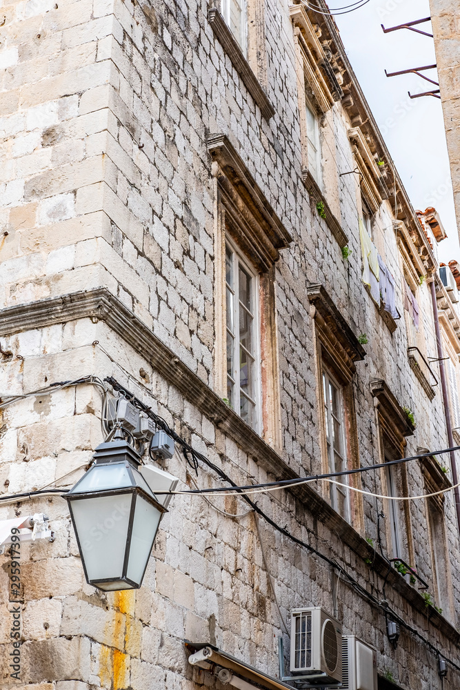 Stone house with lantern in narrow stone street in historic Dubrovnik city, Dalmatia, Croatia, blue sky with clouds, popular touristic destination 