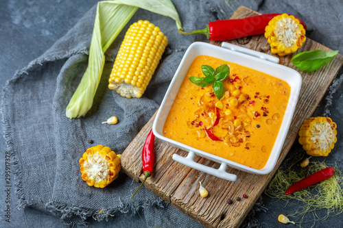 Creamy corn soup with chili in a white bowl.