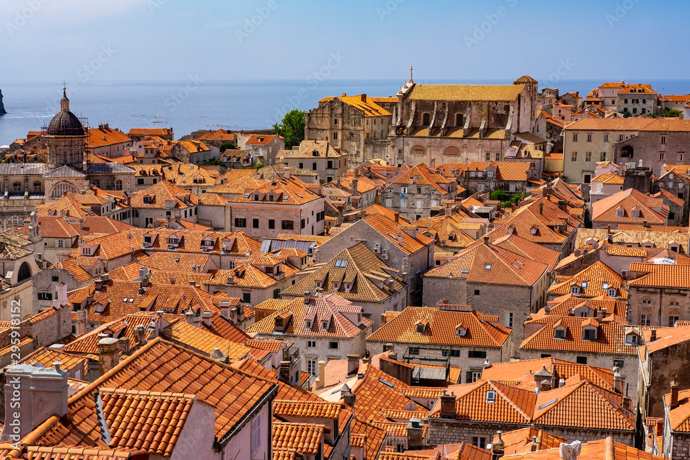 Stone houses with red roofs in old historic Dubrovnik city, Dalmatia, Croatia, blue Adriatic Sea and blue summer sky, the most popular touristic destination