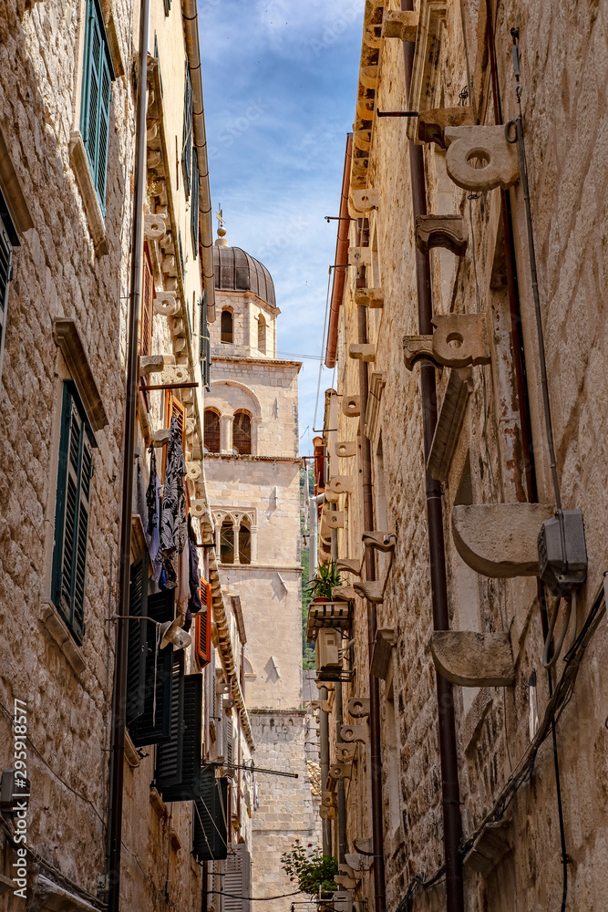 Narrow stone street with stone houses and bell tower in historic old city Dubrovnik, Dalmatia, Croatia, sunny summer day, most popular touristic destination