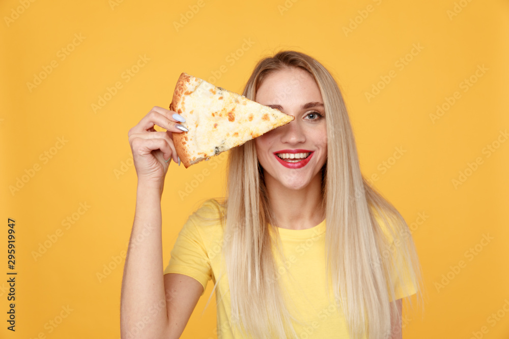 Attractive woman with slice of pizza isolated over the yellow background Attractive woman with slice of pizza isolated over the yellow background