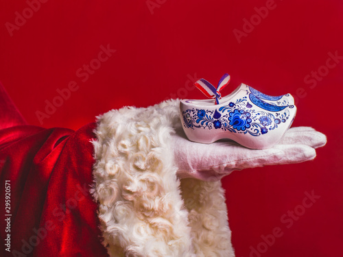 Photography Santa Claus holds in his hand a typical Dutch wooden clogs in the style of Delft Blauw, a traditional souvenir, Christmas holidays