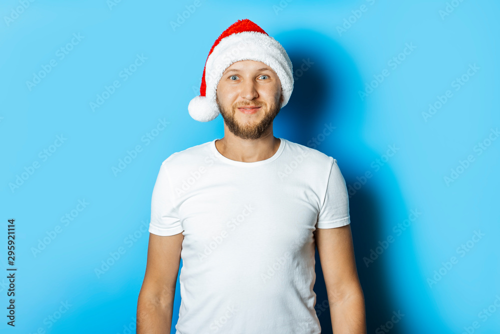 Man in a hat of Santa Claus on a blue background. Concept of winter, autumn, cold, Christmas, winter holidays Man in a hat of Santa Claus on a blue background. Concept of winter, autumn, cold, Christmas, winter holidays
