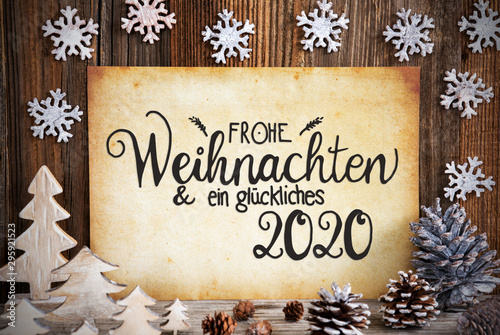 Old Paper With German Text Frohe Weihnachten Und Ein Glueckliches 2020 Means Merry Christmas And Happy 2020. Christmas Decoration Like Tree, Fir Cone And Snowflakes. Brown Wooden Background