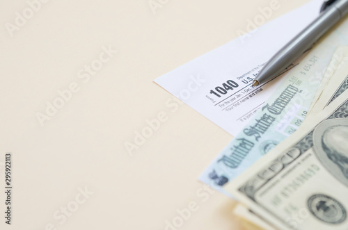 1040 Individual Income tax return form with Refund Check and hundred dollar bills on beige background photo