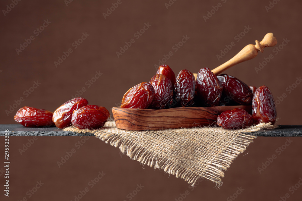  Closeup sweet dried dates in wooden dish. - obrazy, fototapety, plakaty 