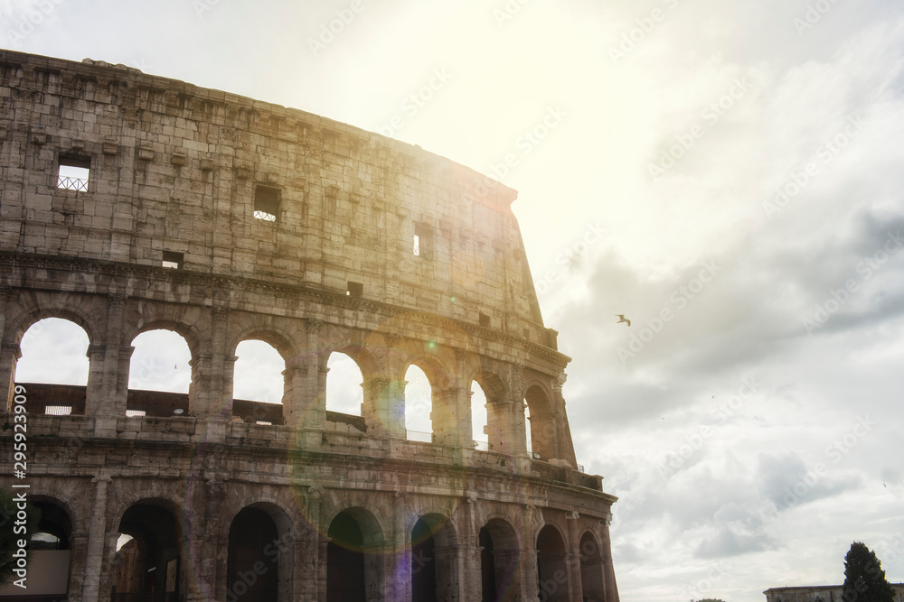 part of the Colosseum in Rome with the sun in front