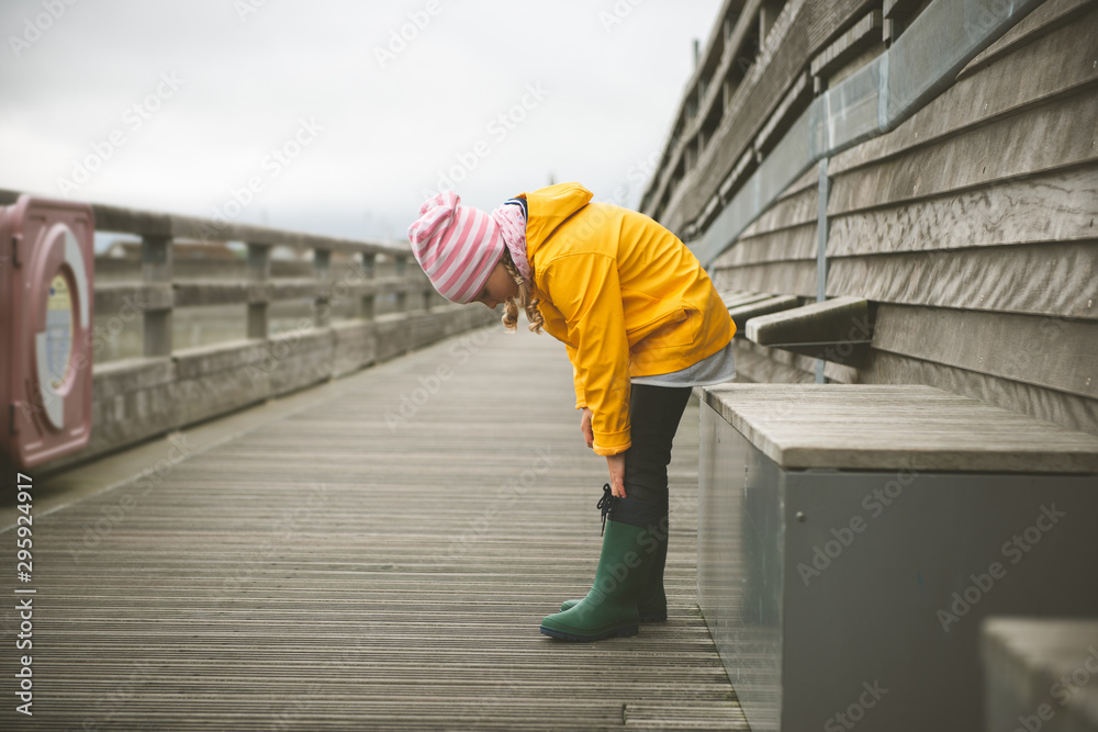 Portrait of little girl in yellow jacket on wooden pier at rainy weather Portrait of little girl in yellow jacket on wooden pier at rainy weather