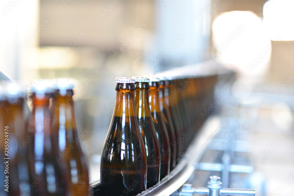 Abfüllen von Bier in Glasflaschen am Fliessband in einer modernen Brauerei // Filling of beer in glass bottles on a conveyor belt in a modern brewery  - obrazy, fototapety, plakaty 