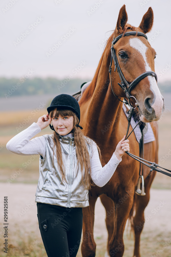 Obraz premium First lessons of horseback riding. Young beautiful girl riding a horse in a field.