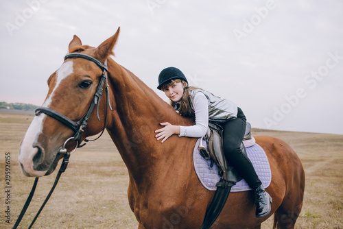 First lessons of horseback riding. Young beautiful girl riding a horse in a field.