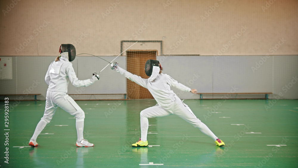 Two fencers are fighting in the school gym Two fencers are fighting in the school gym