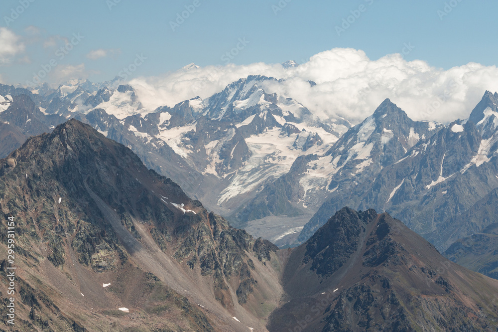 Caucasus mountains near Elbrus volcano with glaciers, clouds and peaks.