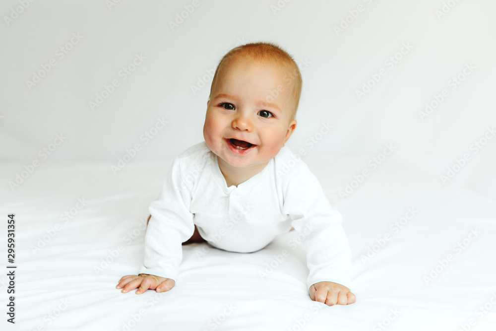 Beautiful happy baby smiling in white on the bed. Beautiful happy baby smiling in white on the bed.