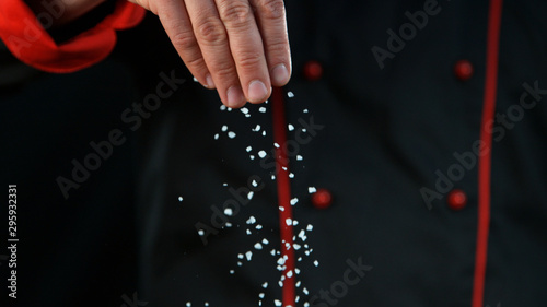 Closeup of chef pouring coarse-grained salt