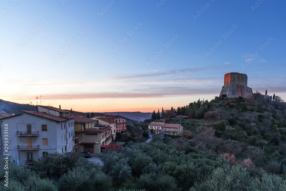 Amazing landscape of the Tuscan countryside with the medieval fortress Rocca of Tentennano on the hill in winter at sunset.