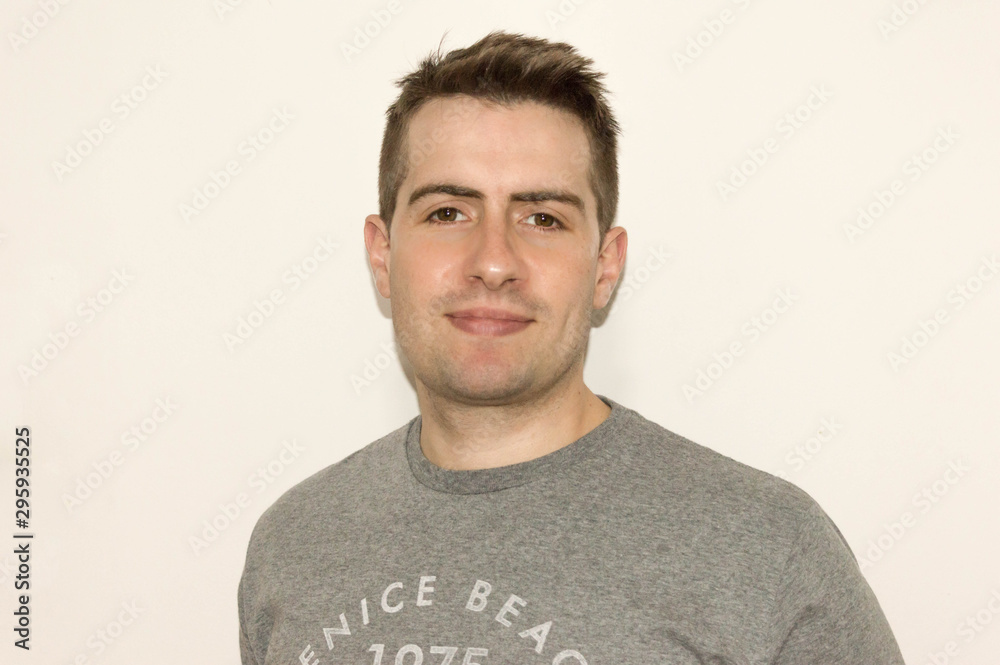 Portrait of smiling young man in gray shirt with a white background Portrait of smiling young man in gray shirt with a white background