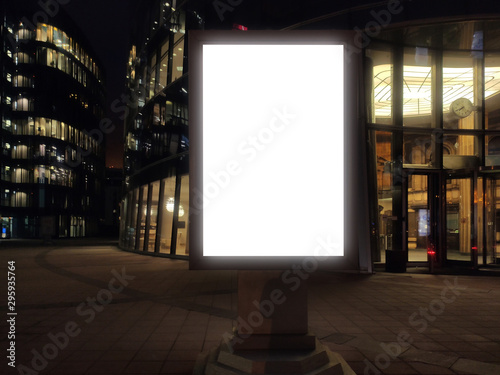 vertical small city billboard advertising city format. mockup at night with white field billboard in a city with a business center glowing advertising box