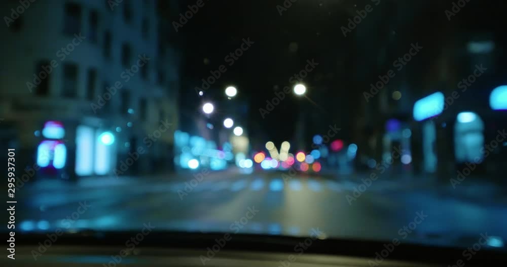 4K - Driving at night on town streets. Front car window with blurred city traffic