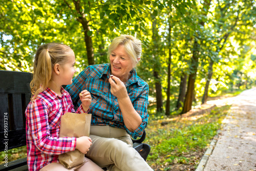 Grandmother and granddaughter having fun while eating popcorn in park