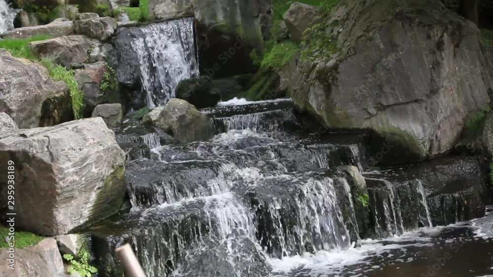 closeup of water falling on rocks in a Japanese garden closeup of water falling on rocks in a Japanese garden