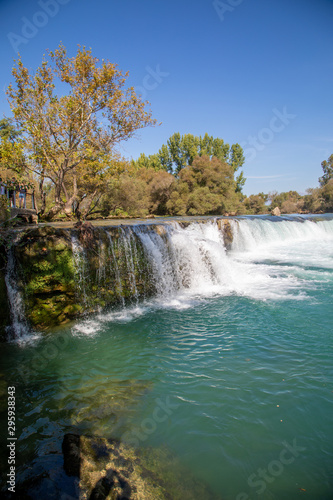 under a bright blue sky you can see the waterfall of Manavgat