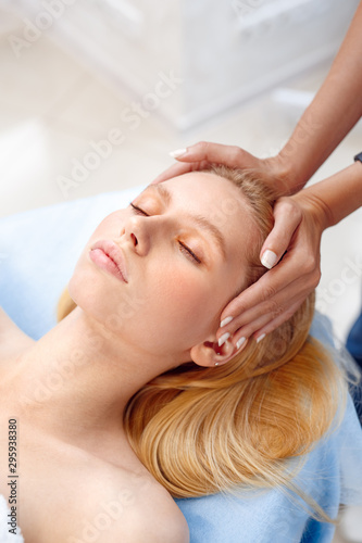 Cosmetology Service. Young woman at beauty clinic lying relaxed while doctor touching head preparation for procedure close-up