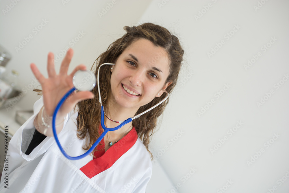 young smiling caucasian nurse shows the stethoscope in her hand in the infirmary young smiling caucasian nurse shows the stethoscope in her hand in the infirmary