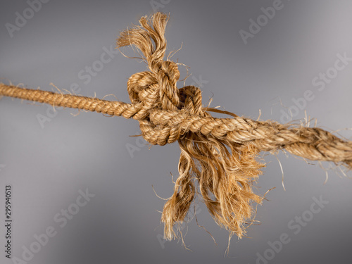 Rough strong ropes connected by large knot on gray background