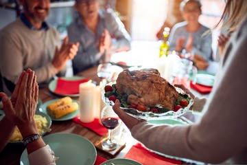 Family and friends dining at home celebrating christmas eve with traditional food and decoration, showing proud turkey cooking