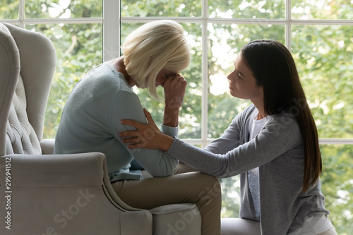 Empathic millennial lady soothing desperate crying mature mother.