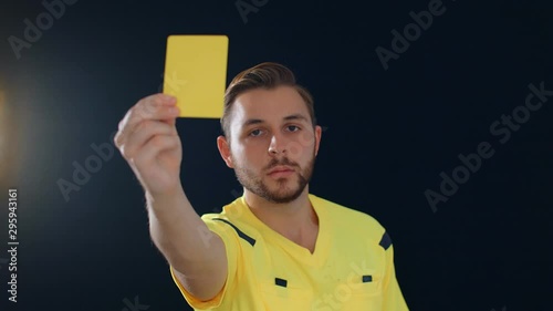 Football Soccer referee on black background showing penalty yellow card, 4k slow motion