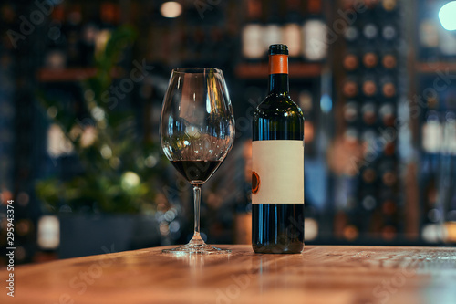 Foto Wine glasss on the wooden table is filled with red wine and ready for tasting