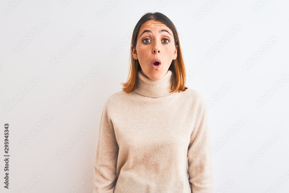 Beautiful redhead woman wearing winter turtleneck sweater over isolated background afraid and shocked with surprise expression, fear and excited face. Beautiful redhead woman wearing winter turtleneck sweater over isolated background afraid and shocked with surprise expression, fear and excited face.