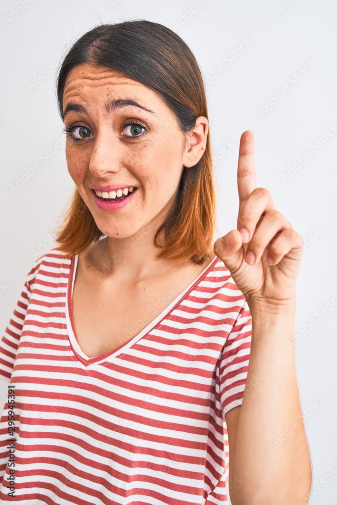 Beautiful redhead woman wearing casual striped red t-shirt over isolated background surprised with an idea or question pointing finger with happy face, number one Beautiful redhead woman wearing casual striped red t-shirt over isolated background surprised with an idea or question pointing finger with happy face, number one